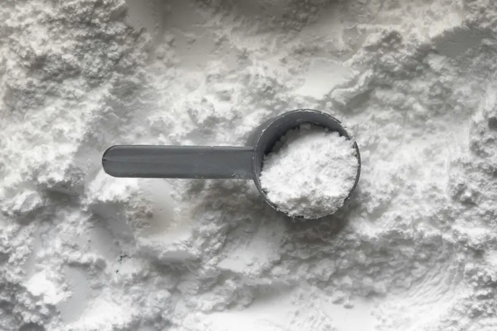 A scoop of fine white powder resting on a pile of the same powder