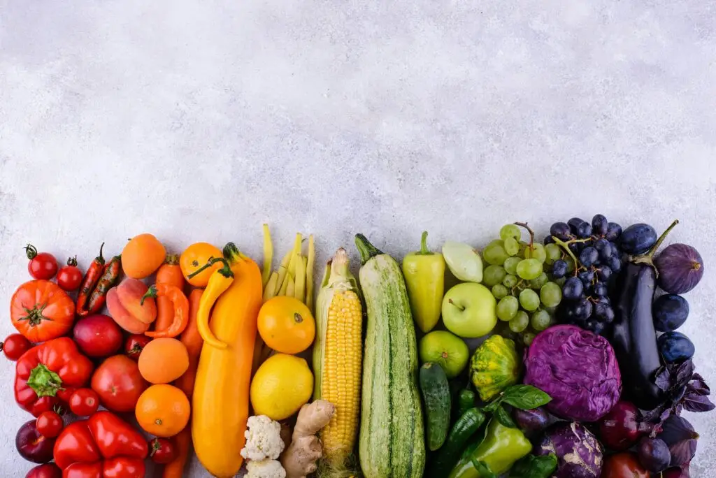 Fruit and vegetables arranged in a line by colour, from red to purple