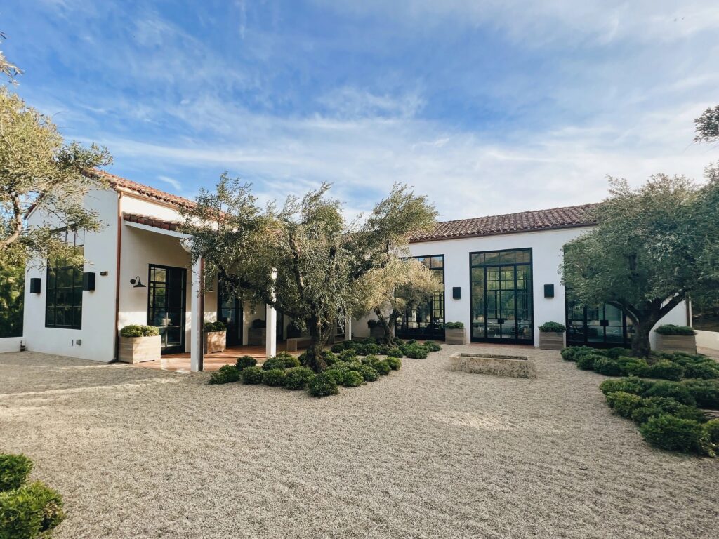 A whitewashed retreat with a gravel courtyard and olive trees