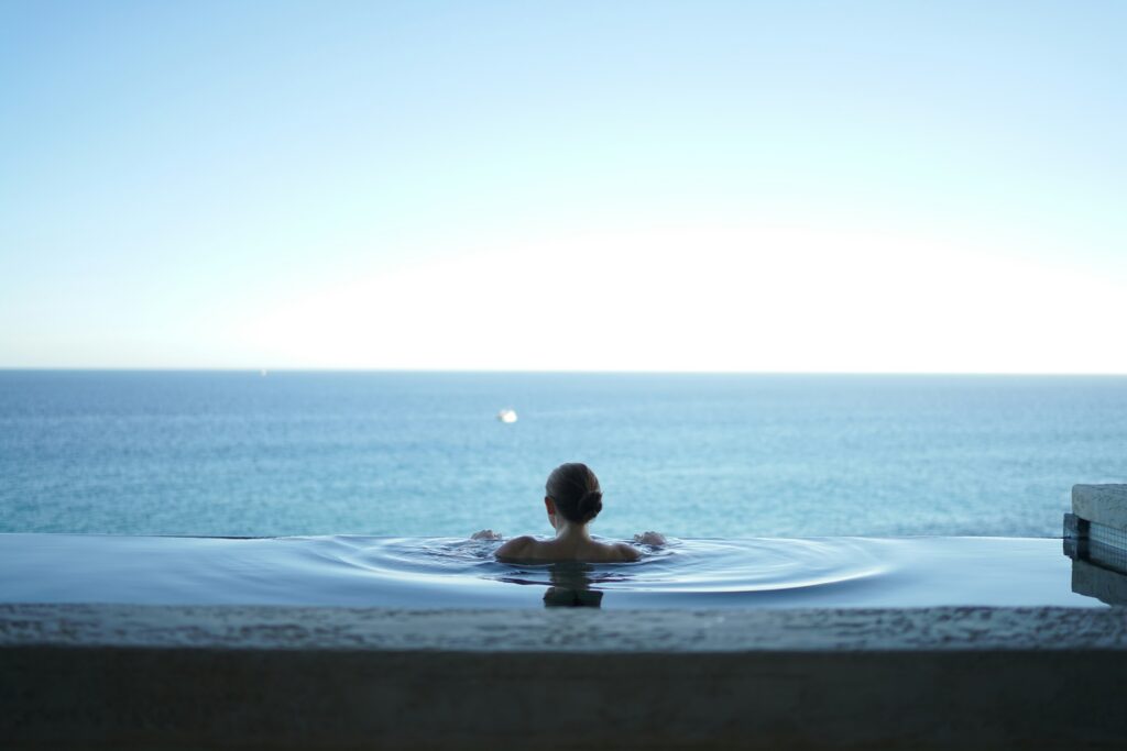 A person alone in an infinity pool looking out over a calm sea