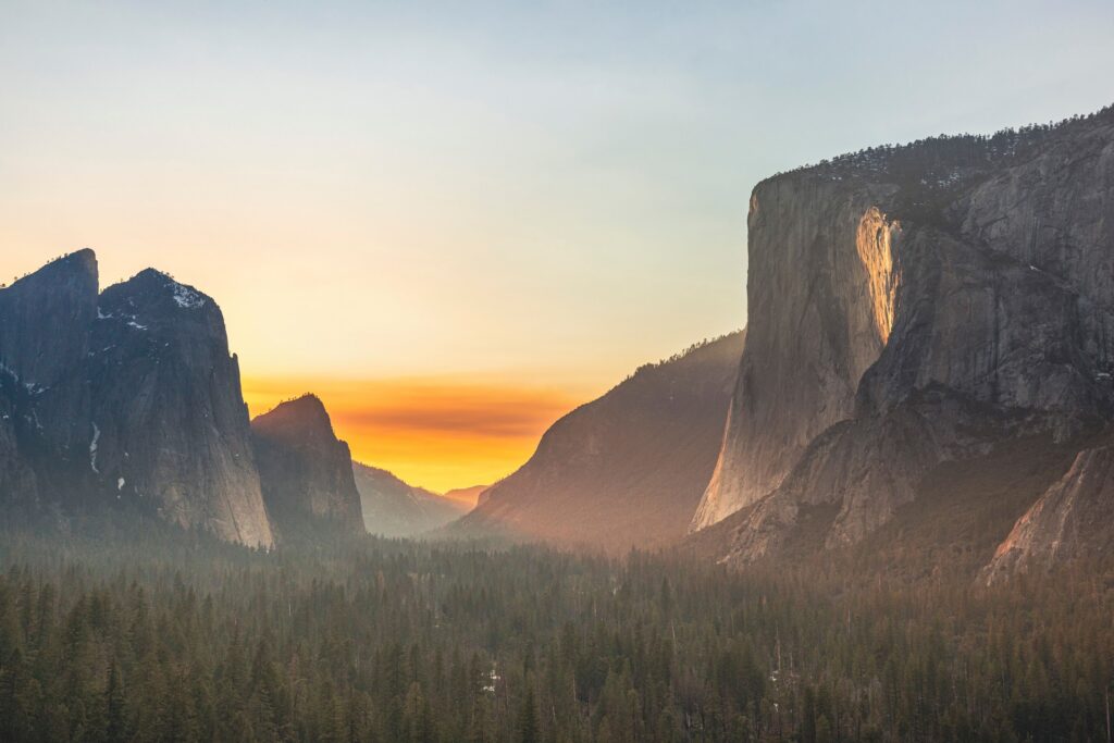 Sunset light on granite cliffs above a quiet forested valley