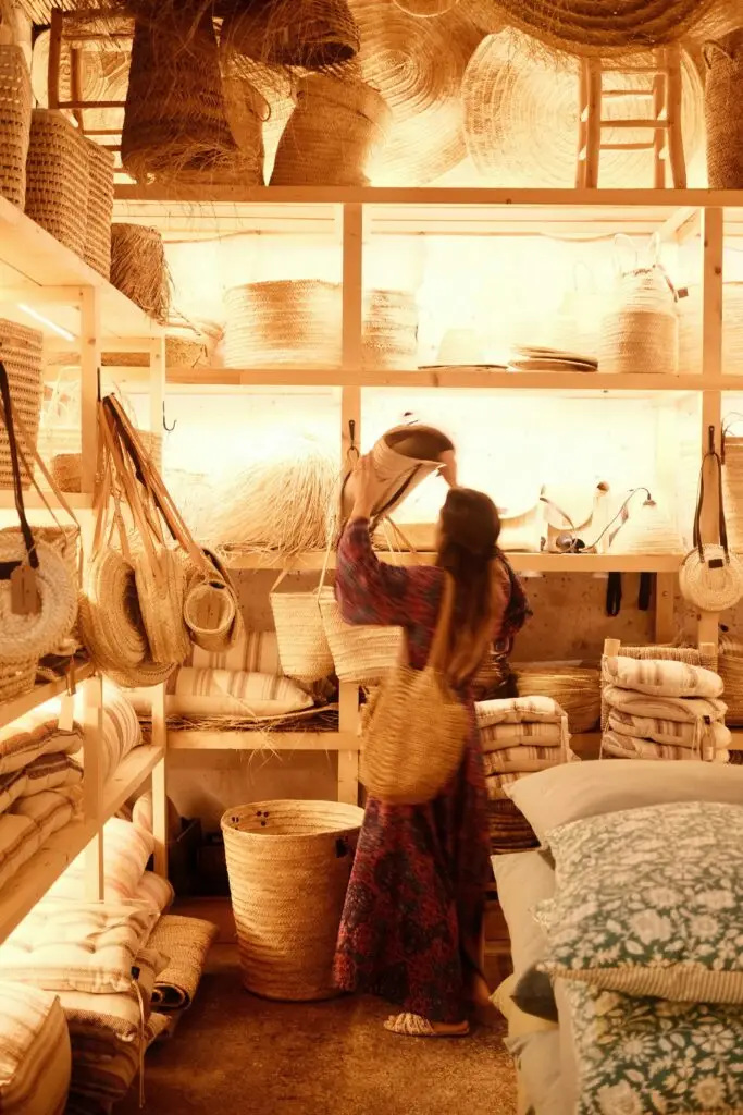 A woman browsing a small independent shop of baskets and textiles