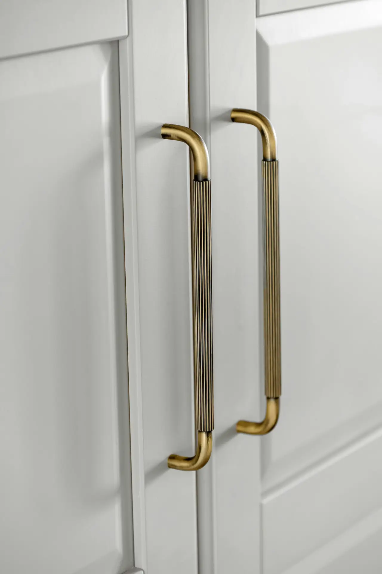 Reeded brass handles on pale painted cabinet doors