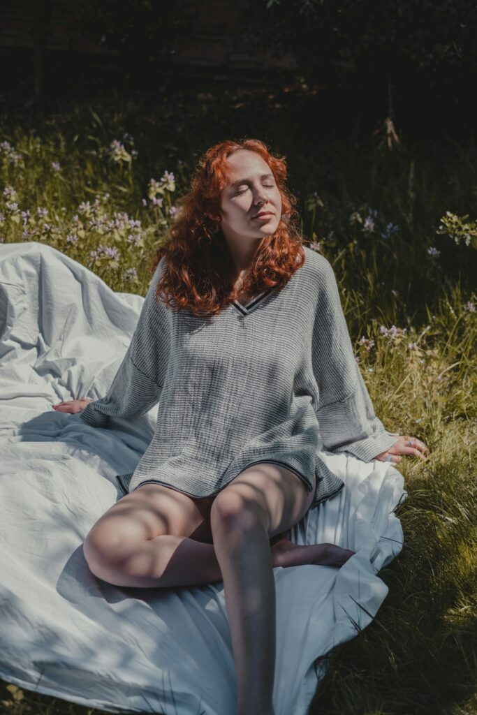 A woman lying back in the sunshine on a blanket in a meadow