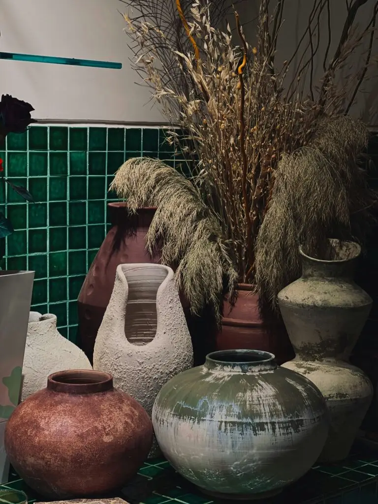 Handmade ceramic vases with dried grasses against green tiles