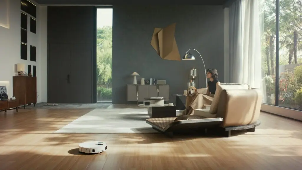 A robot vacuum crossing the oak floor of a calm, light-filled living room