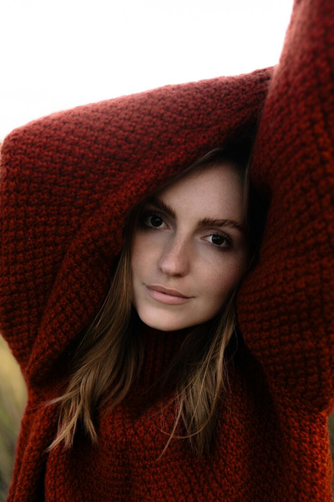 A woman in a deep red knitted jumper pulled up around her head