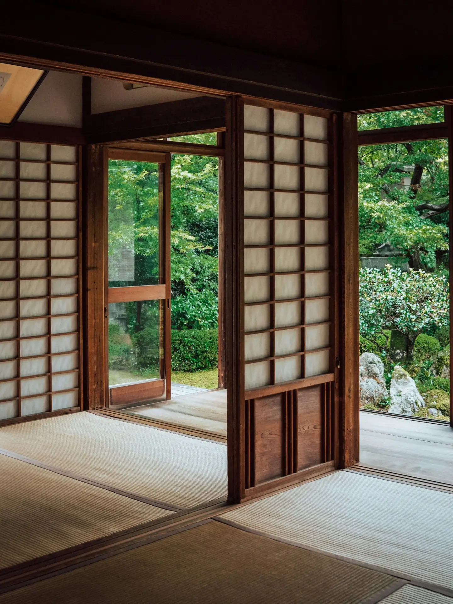 A quiet tatami room with paper screen doors opening onto a green garden