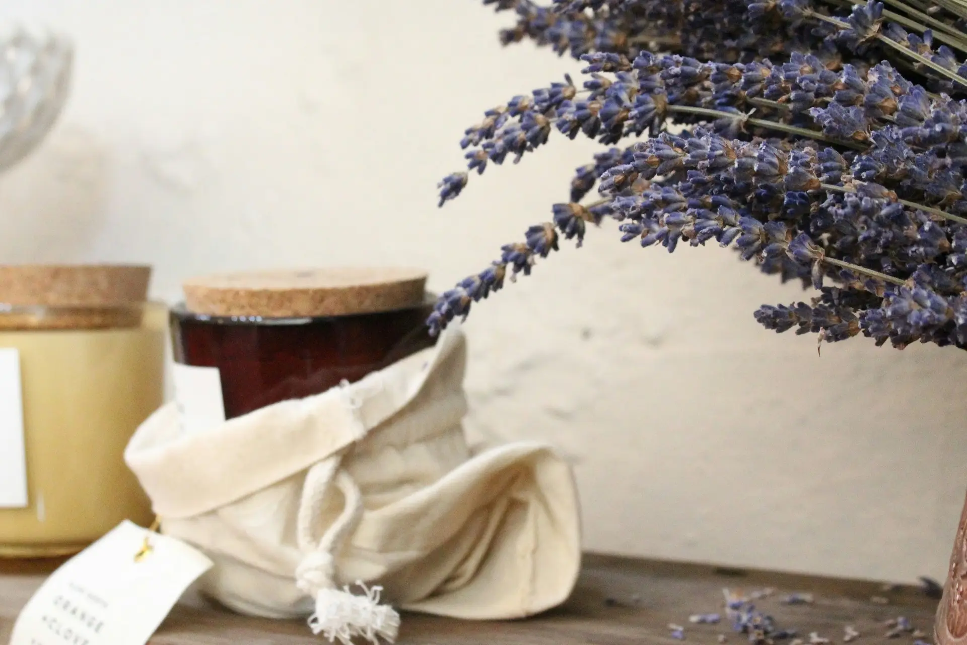 Natural candles with cork lids beside a linen pouch and a bunch of dried lavender
