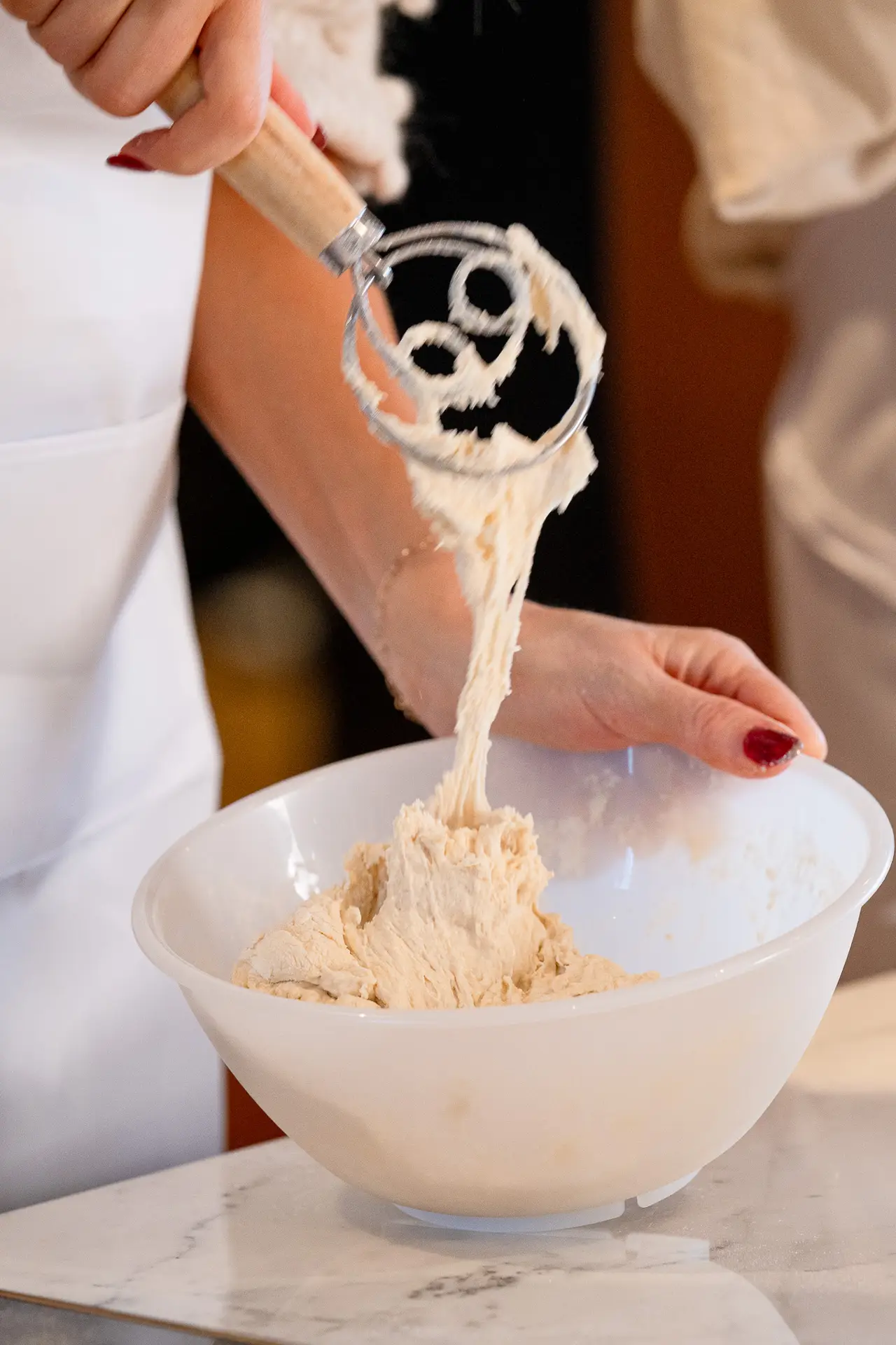 Nina Ross mixing sourdough by hand in a large white bowl