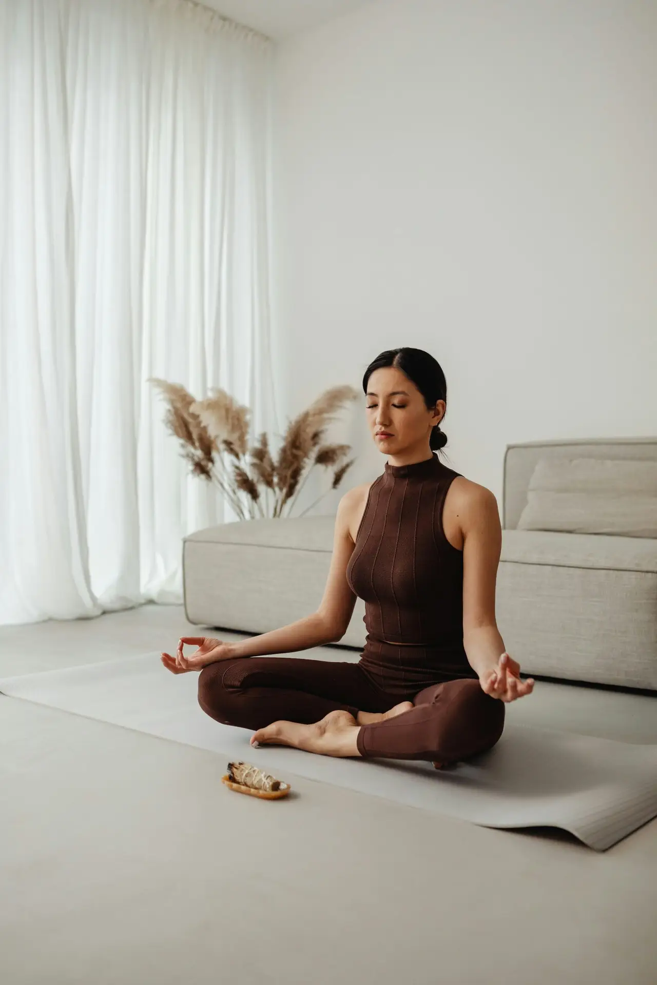 A woman sitting with her eyes closed in a calm, light room