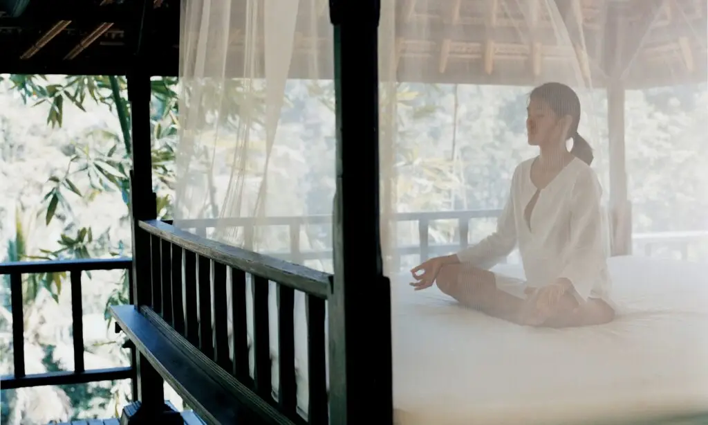 A woman meditating in an open-sided pavilion in the jungle at COMO Shambhala Estate, Bali