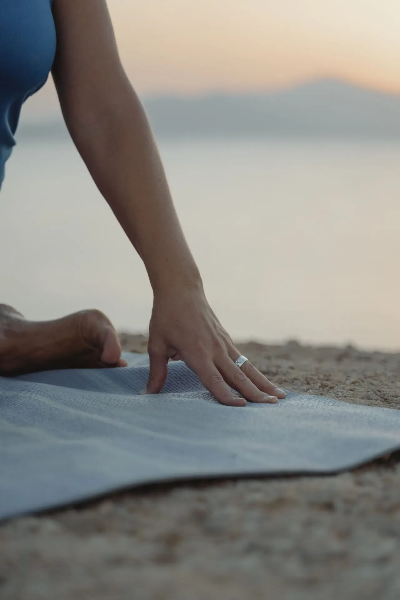A hand wearing a ring resting on a yoga mat