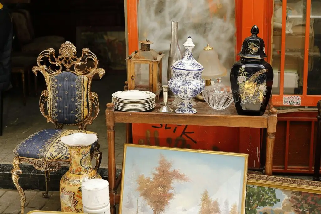 An antiques stall with a gilt chair, vases and paintings