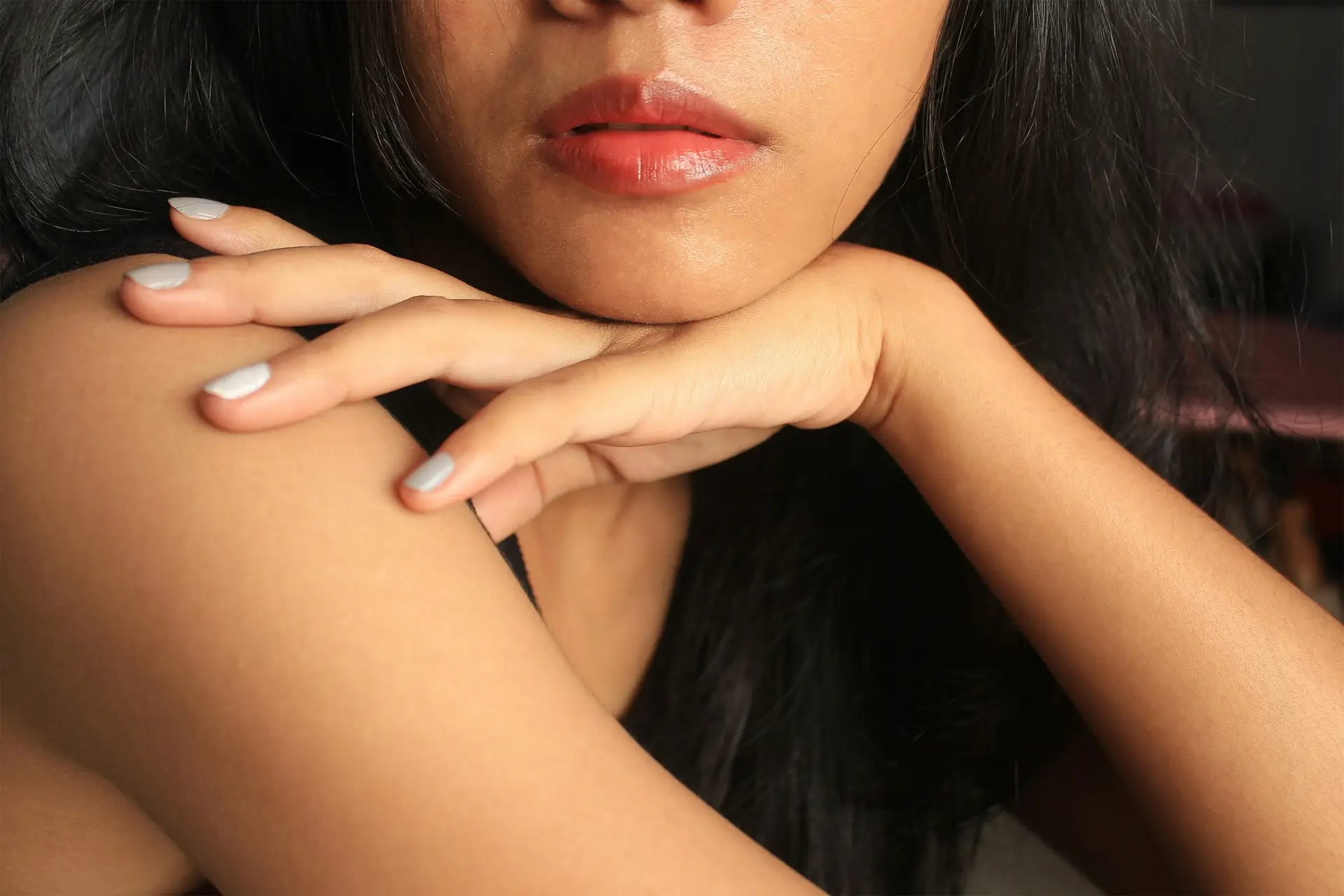 Close-up of a woman resting her chin on her hand, skin glowing