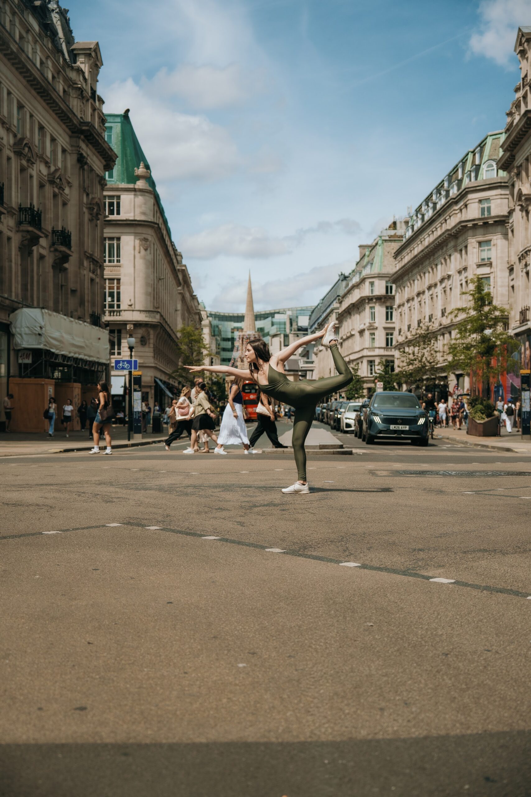 A dancer holding a balance on Regent Street under a bright summer sky